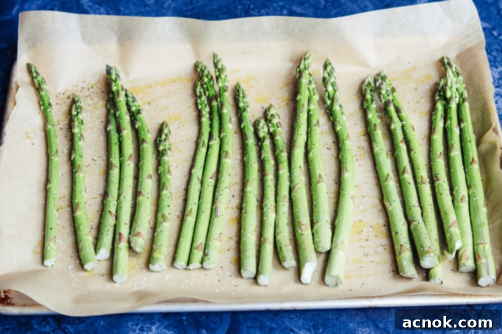 asparagus on baking sheet drizzled with olive oil, salt, and pepper