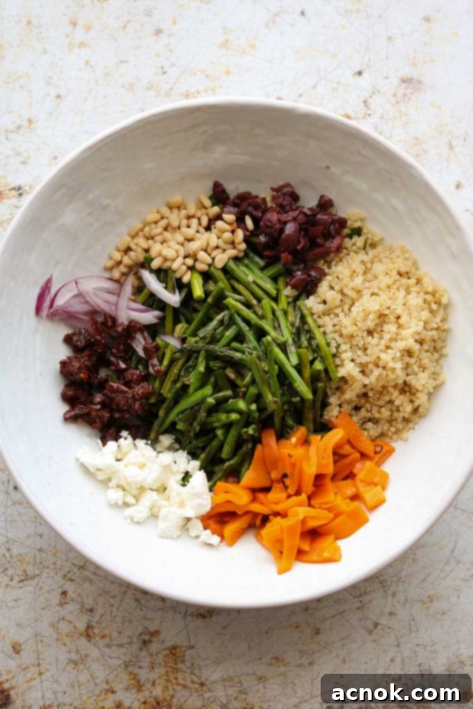 warm quinoa salad ingredients mixed in a large white bowl before dressing
