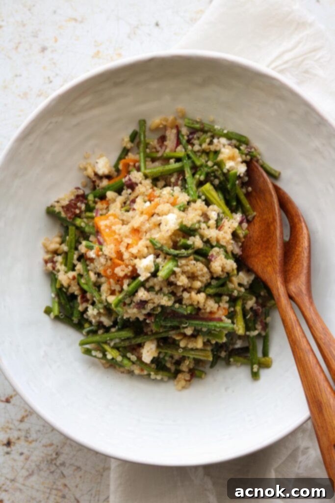 warm quinoa salad in a serving bowl with wooden serving utensils