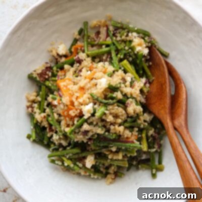 warm quinoa salad in bowl with serving utensils