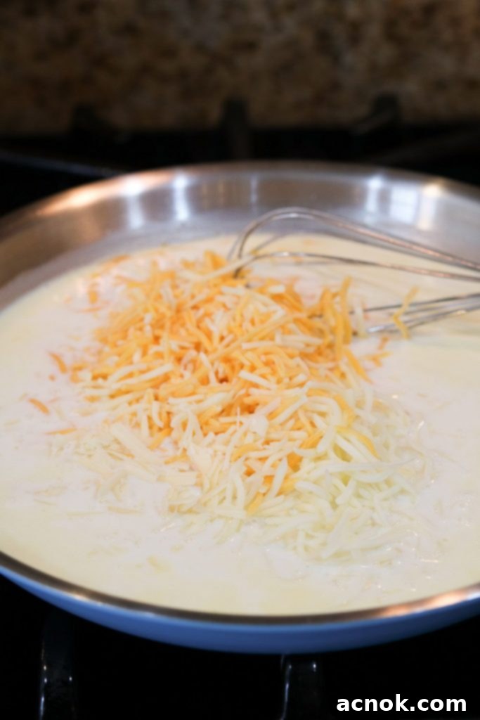 Shredded cheeses melting into a creamy roux base for a rich cheese sauce