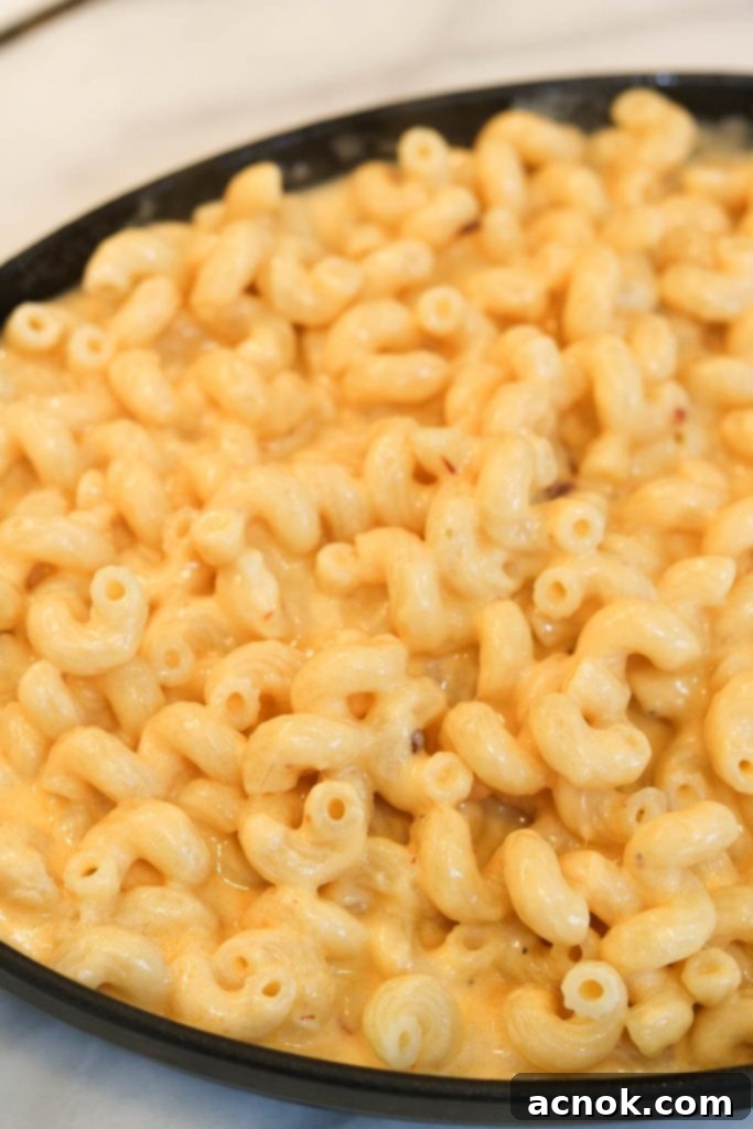 Chipotle cheddar sauce mixed with pasta, ready to be baked into a casserole