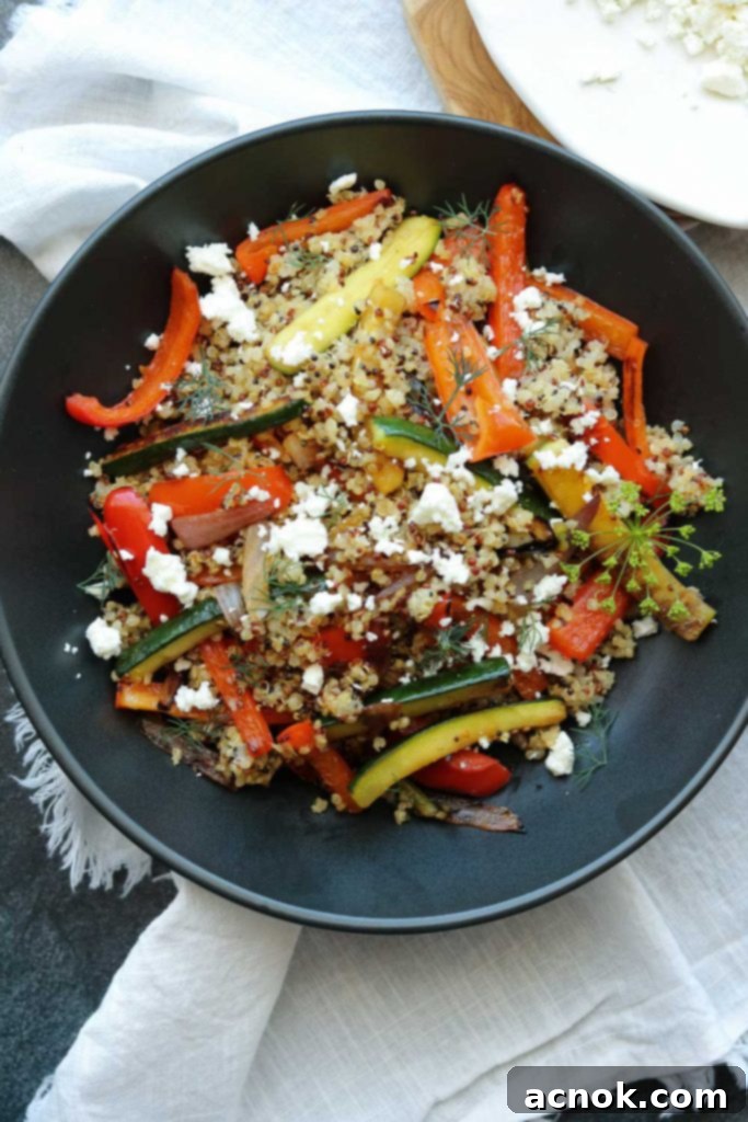 Roasted Vegetable Quinoa with Feta served in a black bowl with a linen napkin, highlighting its fresh ingredients and vibrant colors