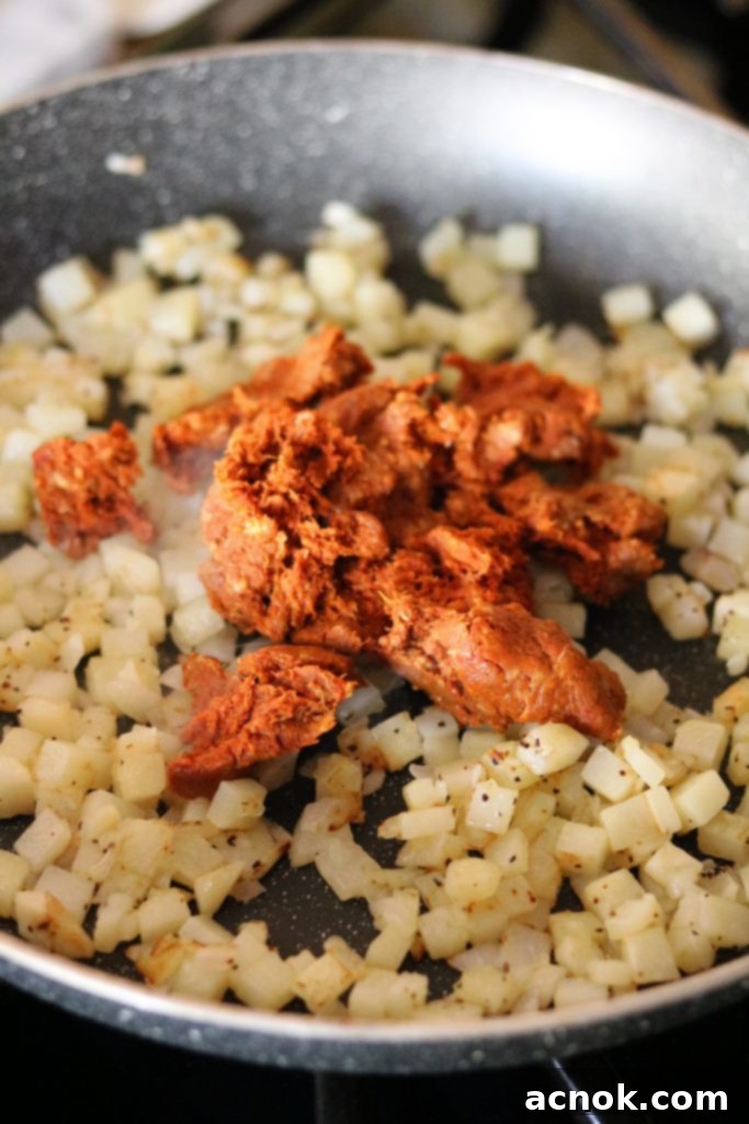 adding chorizo to potatoes and onions in skillet