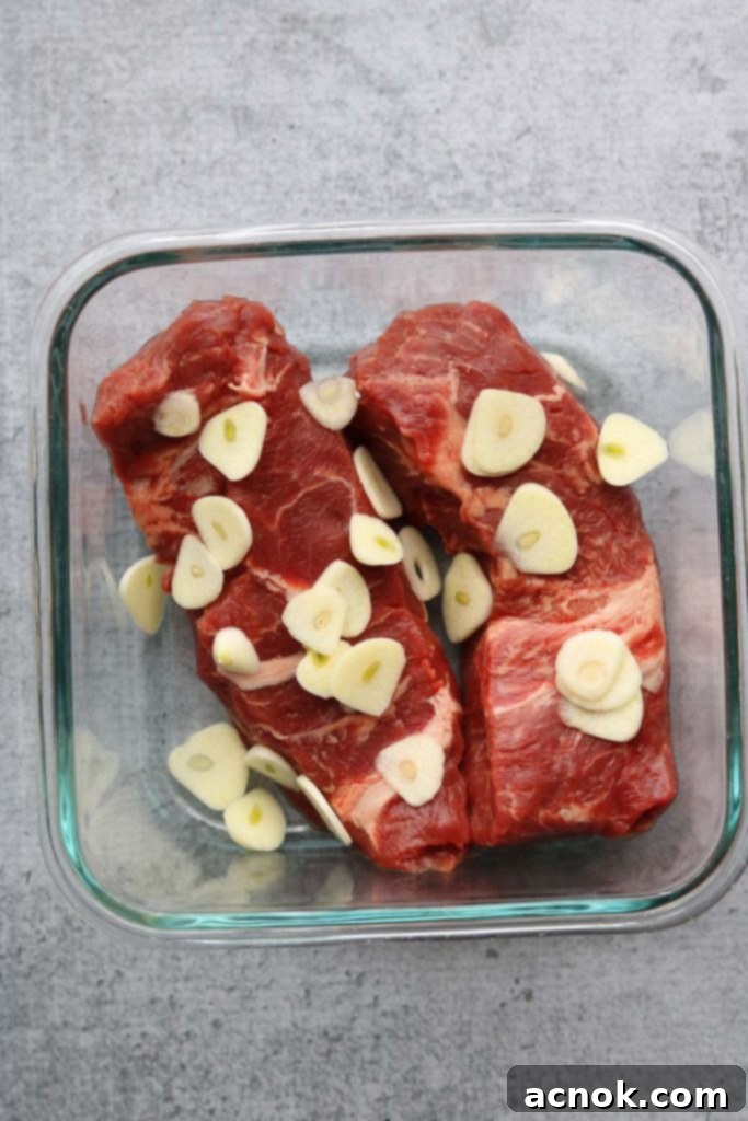 Flat iron steak generously topped with sliced garlic cloves before marinating.