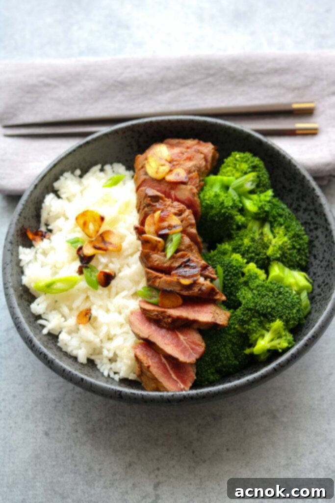 lemon soy flat iron steak with crispy garlic with chopsticks, showcasing the meal ready to eat.