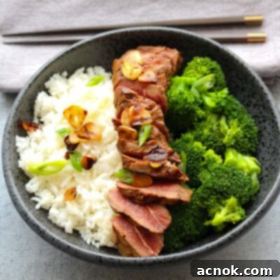 A perfectly cooked lemon soy flat iron steak with crispy garlic, served with chopsticks and a side of rice and broccoli.