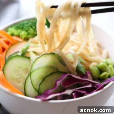 creamy sesame rice noodles in bowl being picked up by chopsticks