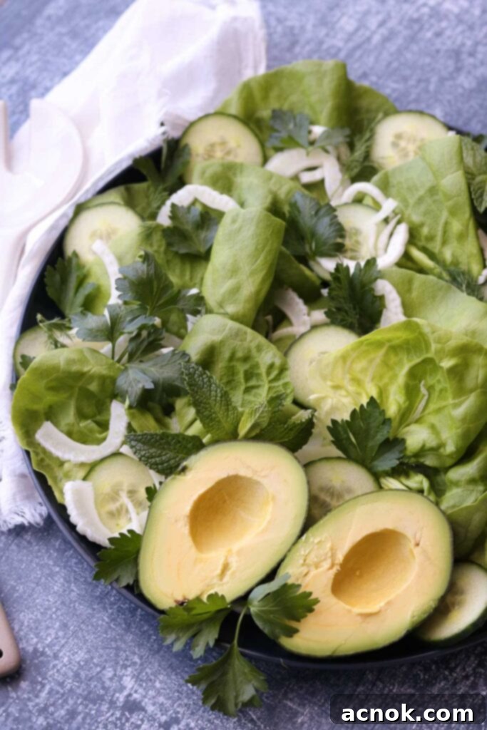 Vibrant green butter lettuce salad on a round platter with elegant serving utensils, showcasing its crisp texture and fresh ingredients.