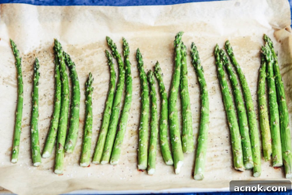 Asparagus roasting in the oven on a baking sheet, partially cooked