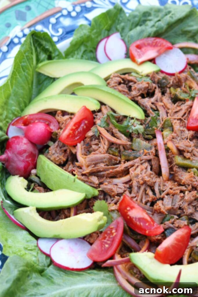 Salpicón de Res in a large bowl with romaine lettuce leaves, avocado, and radishes, beautifully presented.