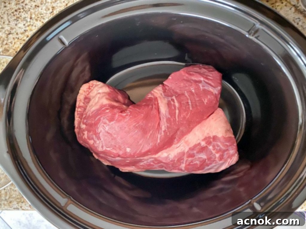 Raw brisket placed in a slow cooker, ready for seasoning.