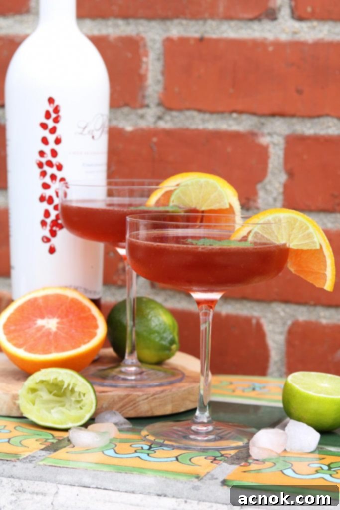 Two Pomerita Cocktails with orange, lime and ice against brick wall