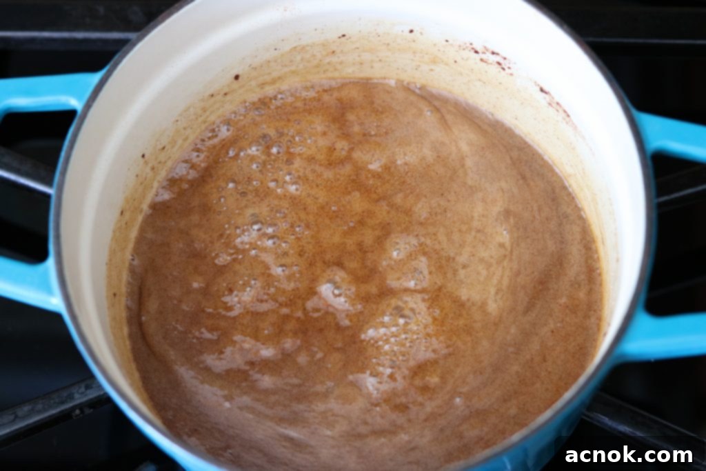 The finished spiced rum butter sauce gently simmering in a pot, now thickened and smooth.