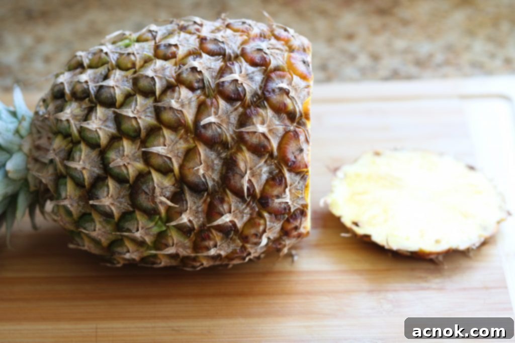 Pineapple on a cutting board with the bottom removed, showing a flat base