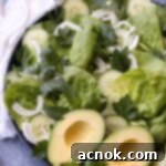 green salad on round platter with serving utensils