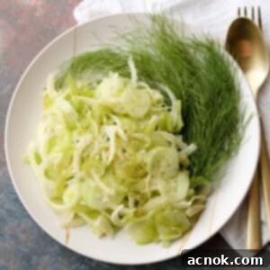Shaved fennel, cucumber, and celery salad garnished with fresh fennel fronds, presented beautifully.