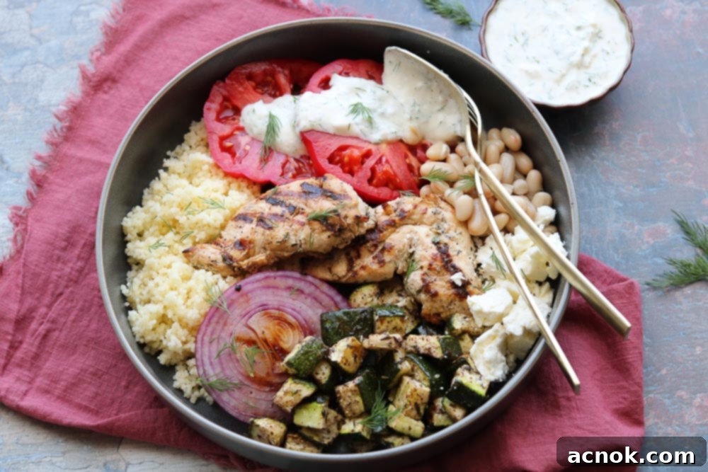 mediterranean grilled chicken bowl with fork on table with napkin and yogurt dill dressing