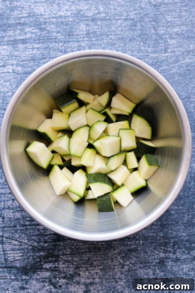 Raw zucchini precisely chopped into uniform 1/2-inch cubes in a clear mixing bowl