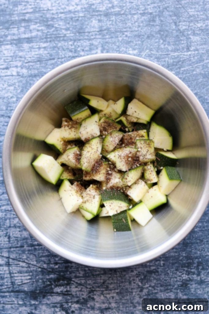 Cubed zucchini generously coated with vibrant Za'atar seasoning and glistening extra virgin olive oil in a mixing bowl