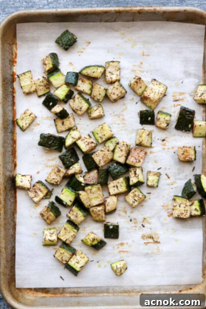 Close-up of golden-brown roasted Za'atar zucchini on a baking sheet, with slightly caramelized edges, fresh out of the oven