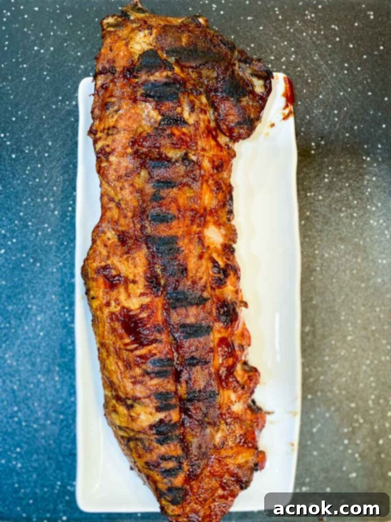 Perfectly cooked BBQ ribs on a platter with a dark, rustic background, showcasing a beautiful char and glistening sauce.