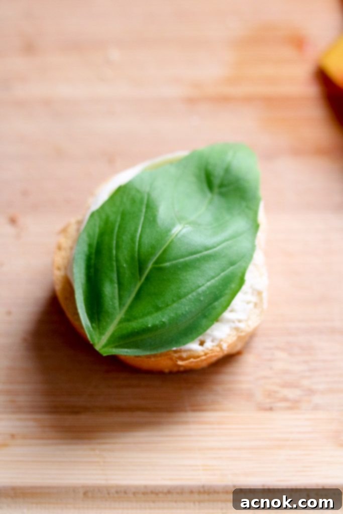 A fresh basil leaf placed on mascarpone spread on crostini