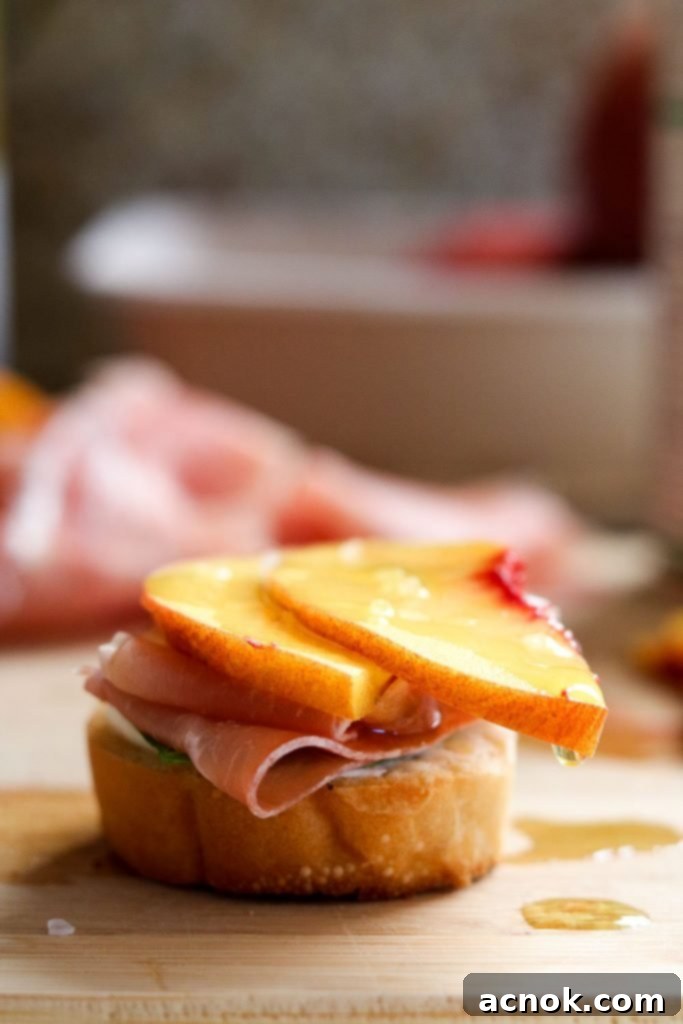 Side view of a finished Peach Prosciutto Mascarpone Crostini, garnished with extra basil