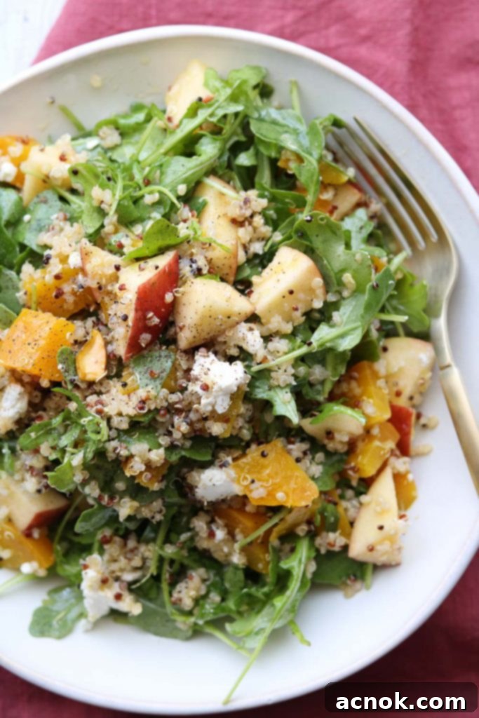 Vibrant roasted golden beet arugula apple salad in a large bowl with a fork, showcasing its colorful ingredients.