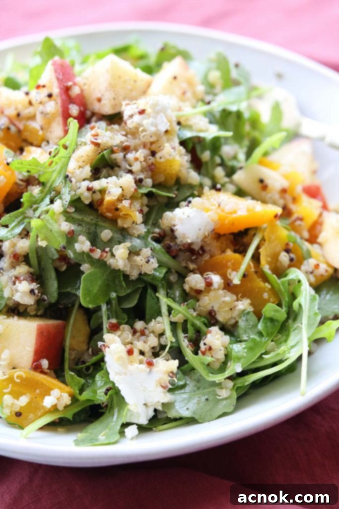 Close-up of a fork lifting a spoonful of roasted golden beet arugula apple salad, showcasing its vibrant ingredients and inviting texture.