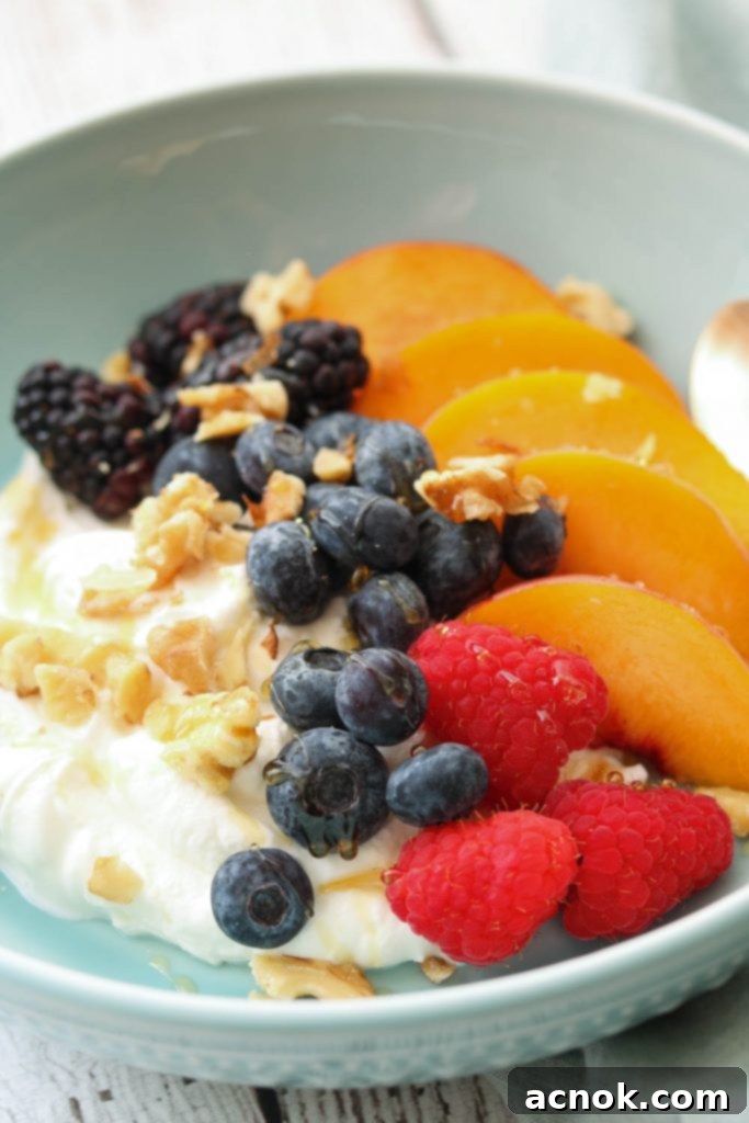 summer fruit yogurt bowl with nuts and spoon