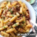 pasta with chicken sun dried tomatoes and garlic in serving bowl with utensils