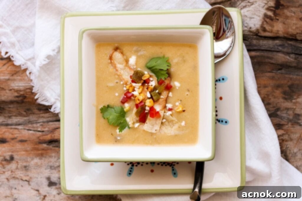 creamy potato hatch chile soup in square bowl with spoon and napkin