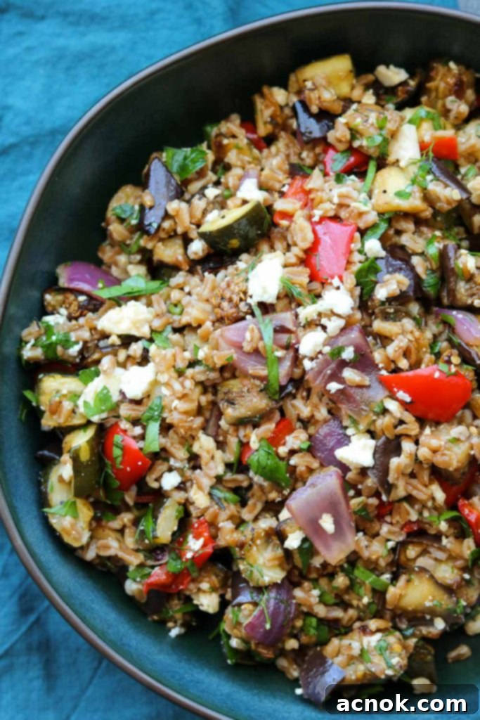 Balsamic Roasted Vegetable Grain Salad in a white bowl with a dark grey napkin beside it, highlighting the vibrant colors of the vegetables and grains.
