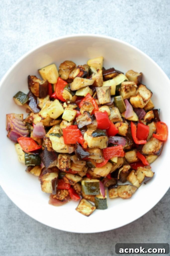 A serving of roasted balsamic vegetables in a white bowl, glistening and ready to be added to the grain salad or enjoyed as a side.