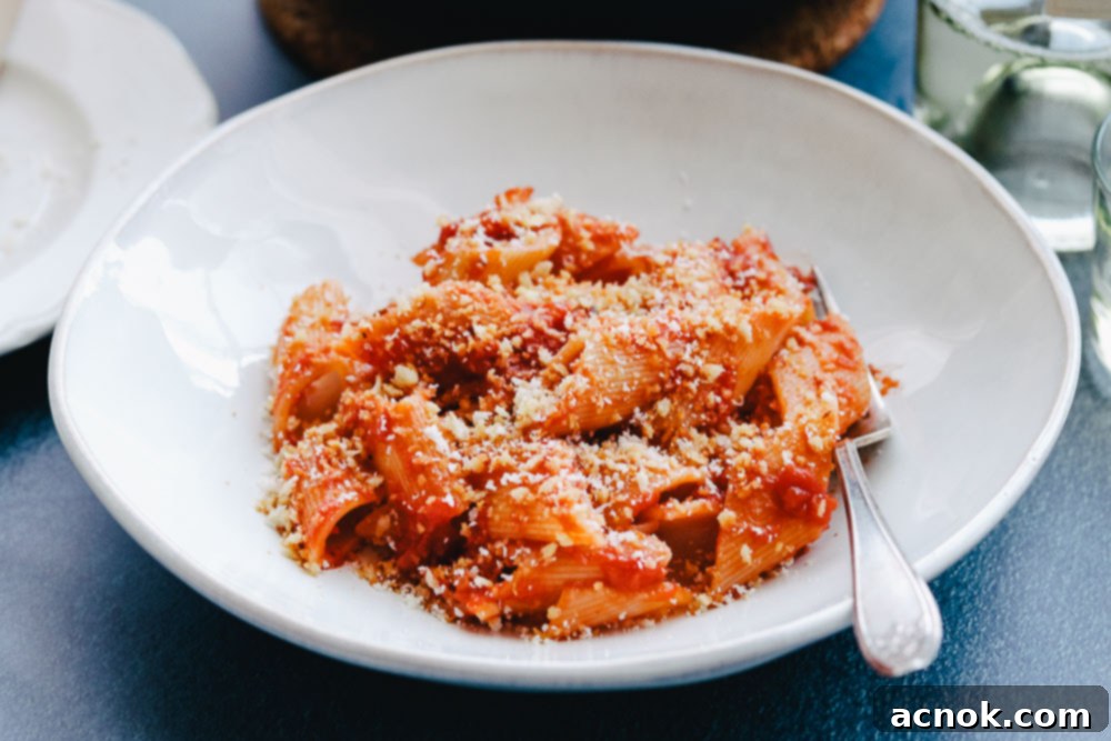 Close-up of Tomato Butter Sauce Pasta with Garlic Breadcrumbs in a white bowl with a fork, showing the rich texture.