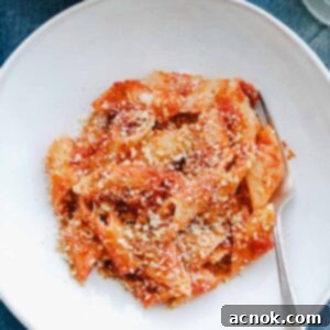 Delicious Tomato Butter Sauce Pasta with Garlic Breadcrumbs in a white bowl with a fork, ready to be enjoyed.