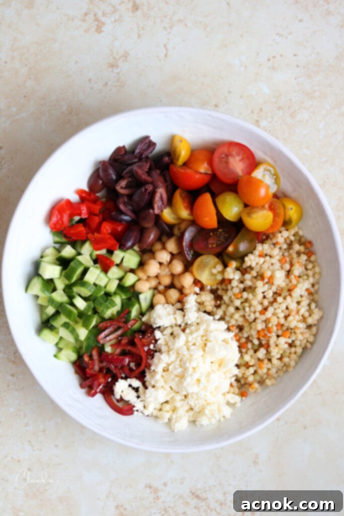 Pearl couscous salad ingredients neatly arranged in a bowl before tossing