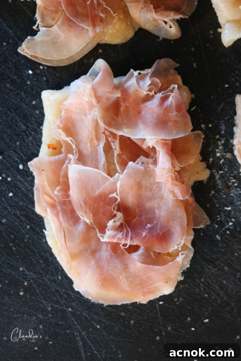 Prosciutto slices placed on a pounded chicken cutlet.