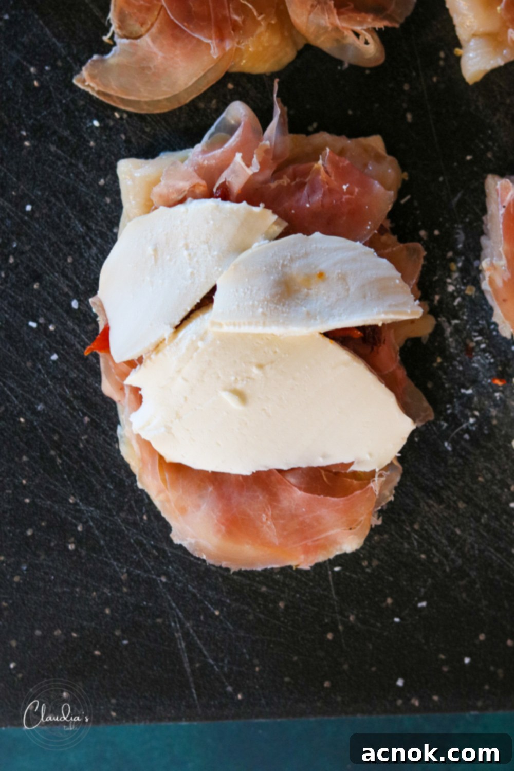 Smoked mozzarella slices placed on top of sun-dried tomatoes, prosciutto, and chicken.