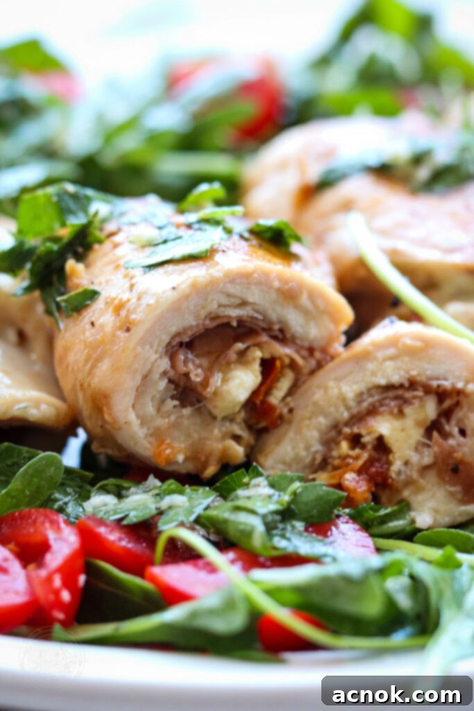 Horizontal photo of grilled chicken involtini sliced in half, showcasing the delicious filling, served with arugula salad.