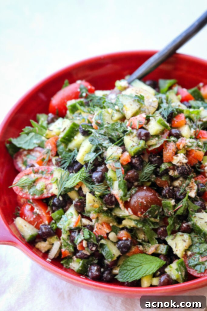 Mediterranean chopped salad with feta in red bowl with feta on white background 