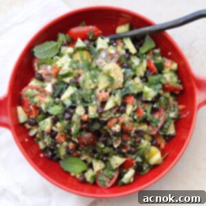 chopped salad in red bowl with black serving spoon