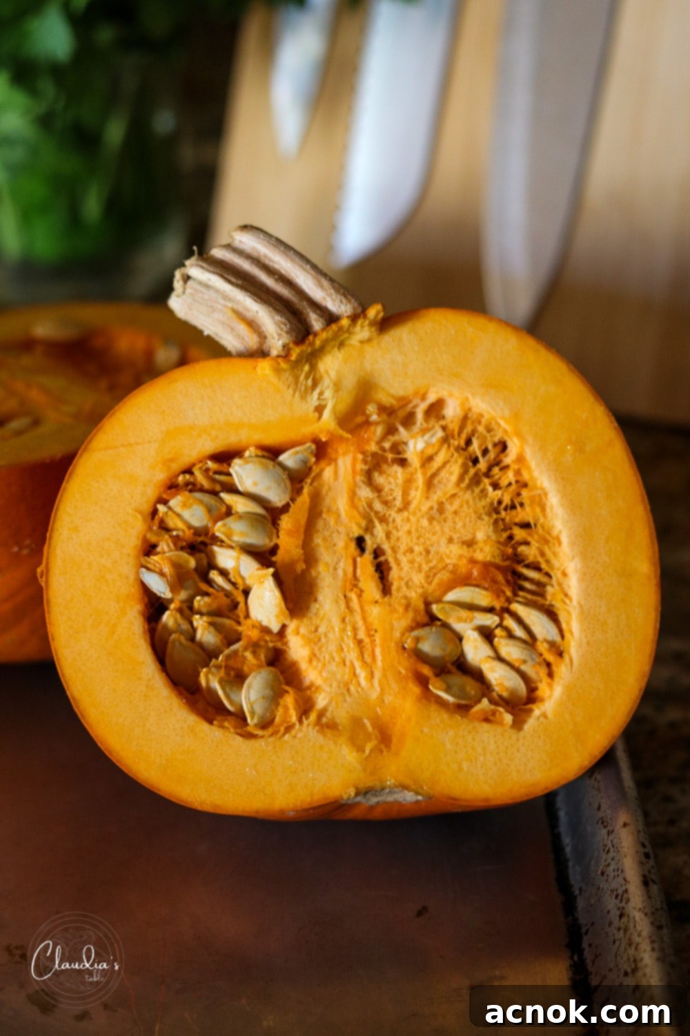 Sugar pie pumpkin sliced in half, showing the inner cavity and seeds, a step in preparing pumpkin for risotto.