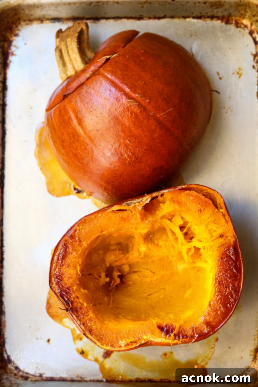 Roasted sugar pie pumpkin halves on a baking sheet, cut side down, golden brown and tender, ready for scooping for pumpkin risotto.