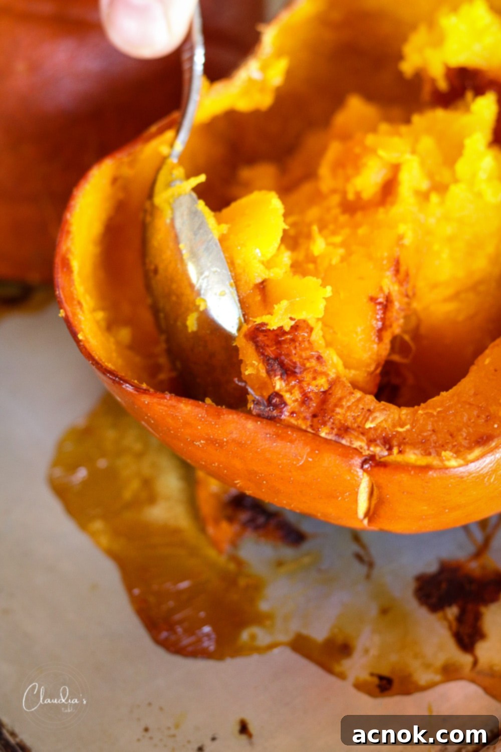 Scooping roasted pumpkin flesh from the skin into a bowl, demonstrating the process for making pumpkin puree for risotto.