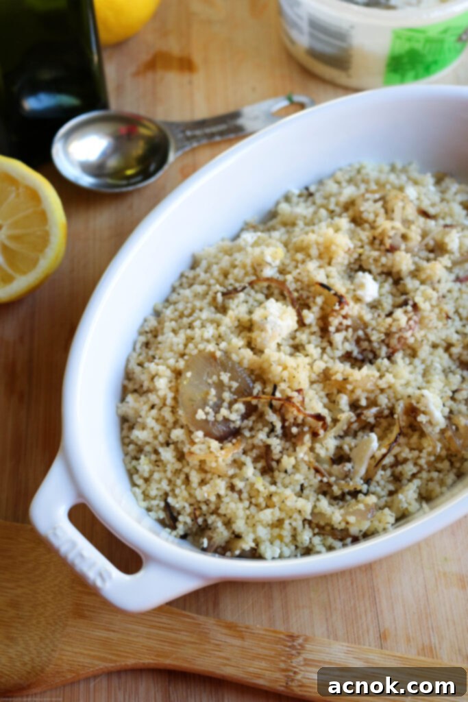 Close-up of fluffy Couscous with caramelized red onions and crumbled feta cheese, ready to serve.