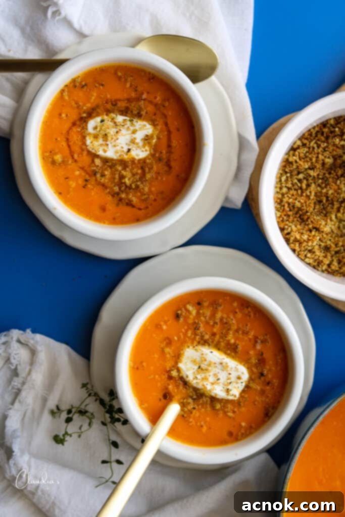 two bowls of roasted carrot and sweet potato soup with spoons 