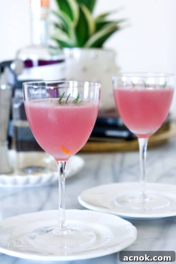 Two simple Meyer lemon gimlet cocktails on white plates, garnished with rosemary and lemon zest.