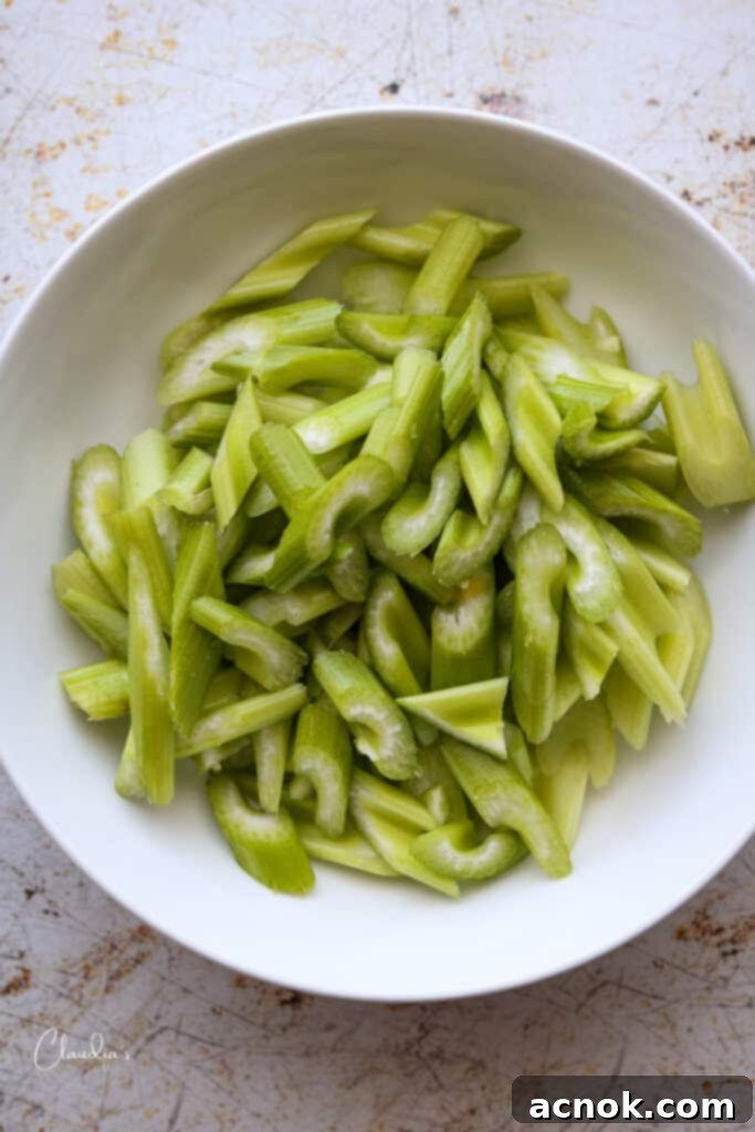 Fresh celery stalks chopped at an angle into half-inch pieces, a key crunchy ingredient for the stir-fry.